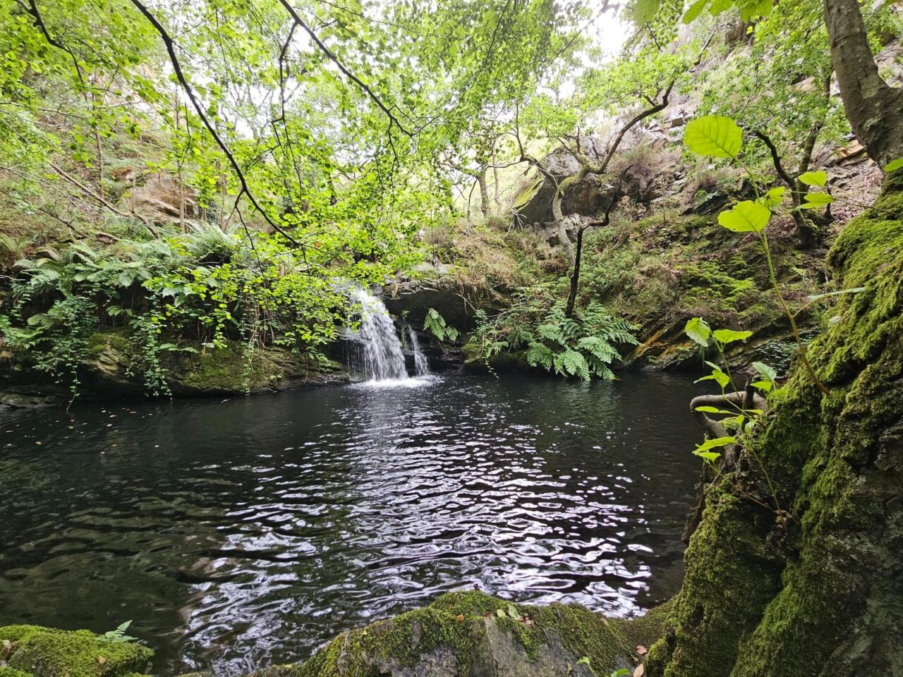Cascada de Zaramatu: el agua cae entre rocas cubiertas de musgo rodeadas de vegetación frondosa