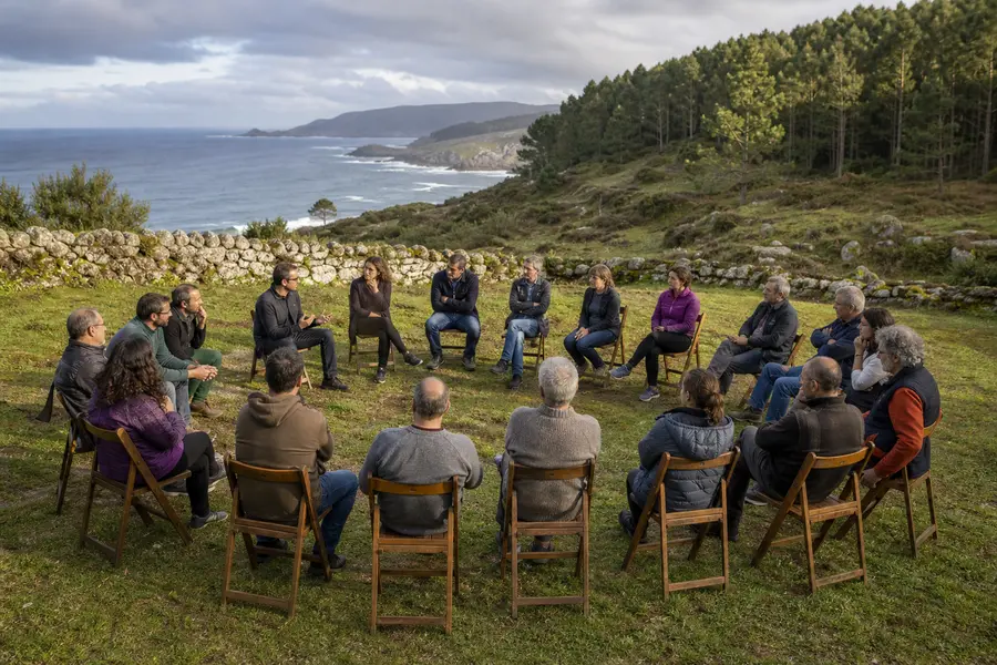 Personas sentadas en círculo en una reunión vecinal al aire libre